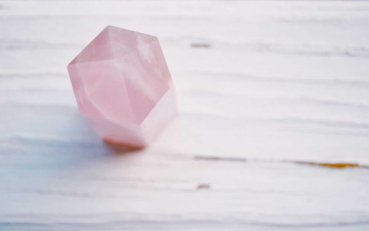 About A pastel pink crystal with a soft focus on a textured surface, perfect for meditation themes.