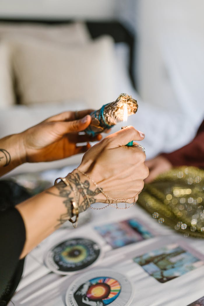 Services Close-up of tattooed hands lighting Palo Santo during a spiritual ritual indoors.